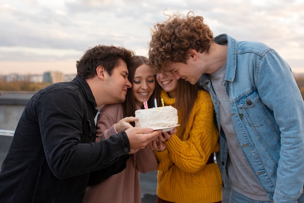 Foto amigos felizes com tiro médio e bolo