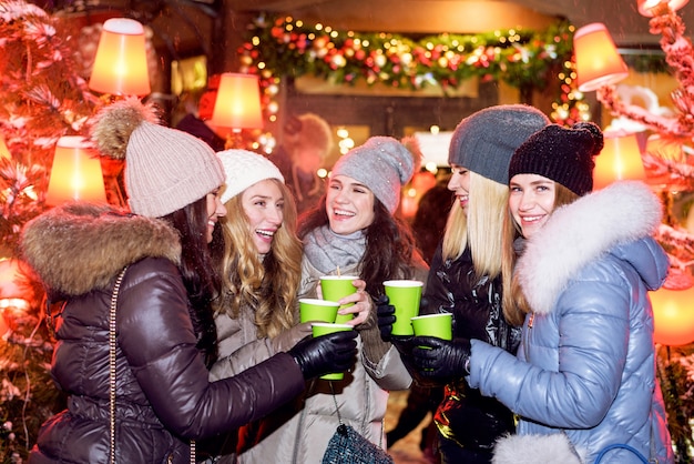 Amigos felizes das mulheres que comemoram no mercado do Natal