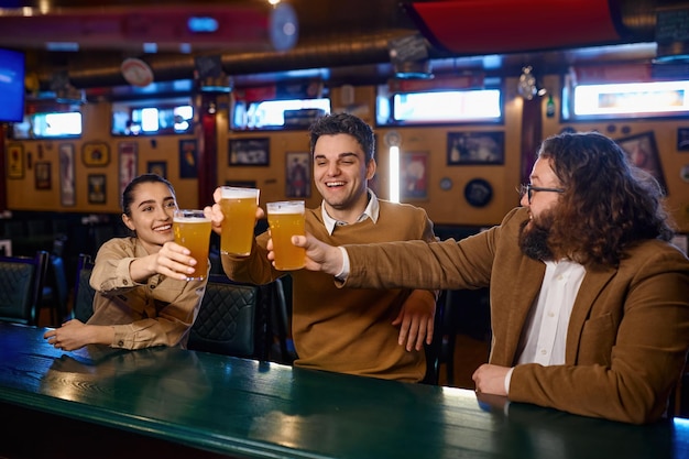 Amigos felizes descansando e conversando no bar. Grupo de pessoas animadas tendo pub de cervejas. Amizade e diversão juntos