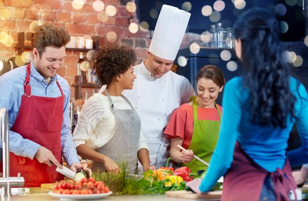 Foto amigos felizes e cozinheiro cozinhando na cozinha