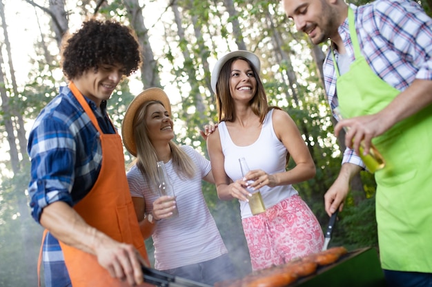 Amigos felizes fazendo churrasco e almoçando na natureza