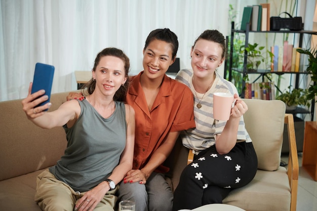 Amigos felizes fazendo retrato de selfie em smartphone