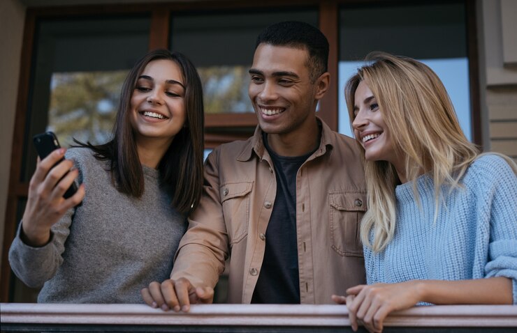 Foto amigos felizes hipster multirraciais usando smartphone, comunicação juntos, assistindo vídeos