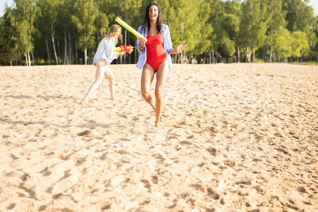 Amigos felizes lutando com armas de água - juventude, estilo de vida de verão e conceito de férias