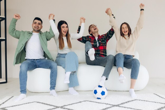 Amigos felizes ou fãs de futebol assistem futebol na TV e comemoram emocionalmente a vitória em casa O conceito de esportes de amizade e entretenimento