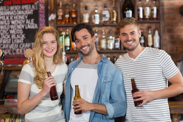 Amigos felizes posando com garrafas de cerveja no pub