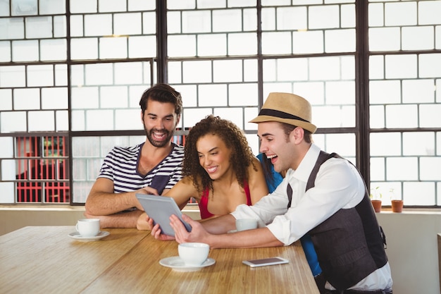 Amigos felizes rindo enquanto olham para o tablet