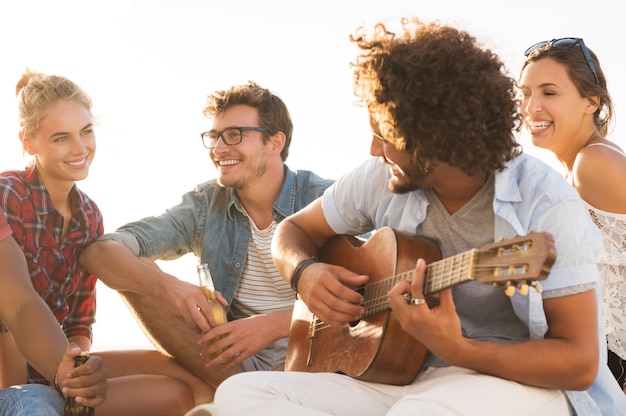 Amigos felizes se divertindo juntos enquanto um cara toca guitarra