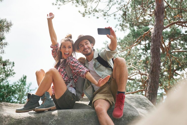 Foto amigos felizes tirando selfie sentados em uma rocha na floresta.