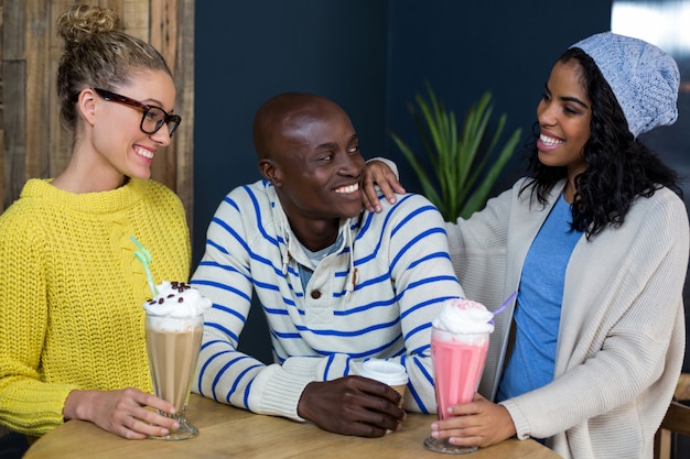 Amigos felizes tomando café e milk-shakes no café