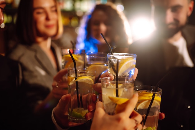 Amigos felizes, torcendo e bebendo coquetéis, curtindo a festa no clube Conceito de estilo de vida da juventude