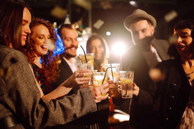 Amigos felizes torcendo e bebendo coquetéis curtindo a festa no conceito de estilo de vida da juventude do clube.