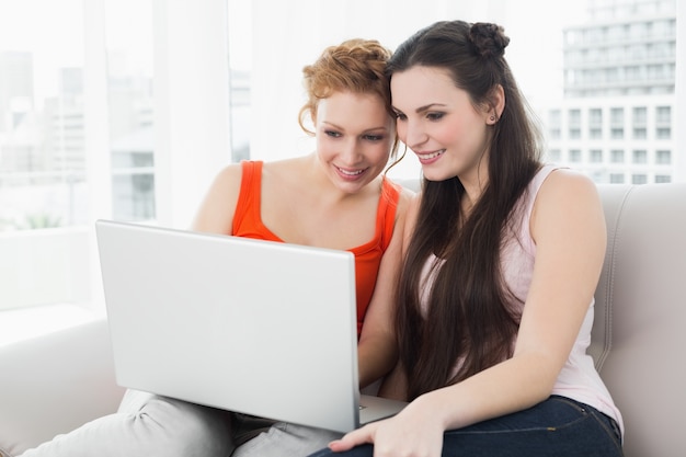 Amigos femininas usando laptop juntos em casa