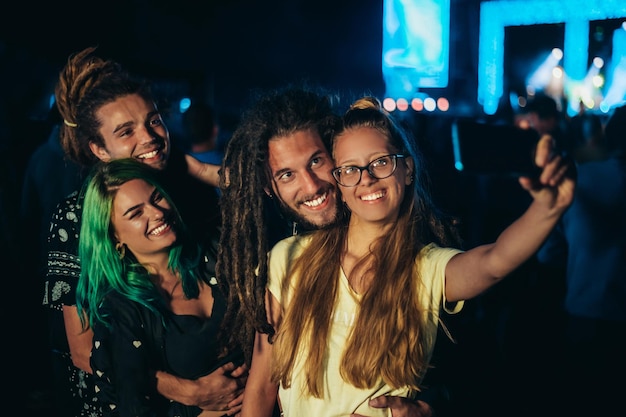 Amigos en el festival de música de verano tomando selfie con un teléfono inteligente