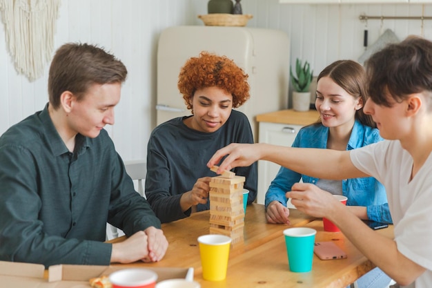 Foto amigos de la fiesta en casa pasando tiempo juntos jugando en un juego de mesa torre de madera en casa feliz div