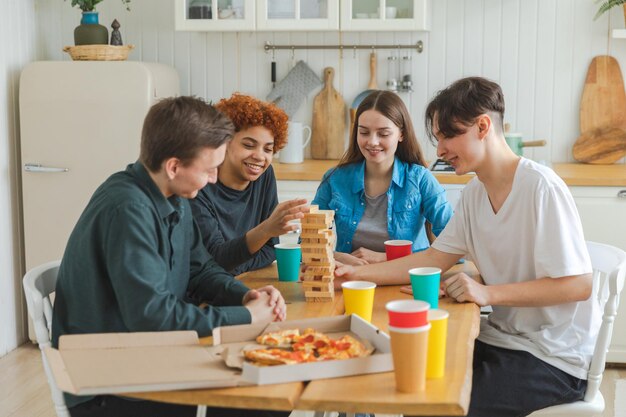 Amigos de la fiesta en casa pasando tiempo juntos jugando en un juego de mesa torre de madera en casa feliz div