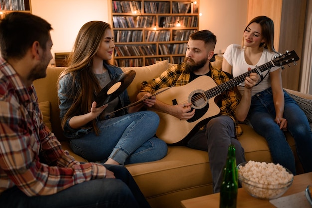 Amigos en una fiesta en casa tocando la guitarra y bebiendo cerveza