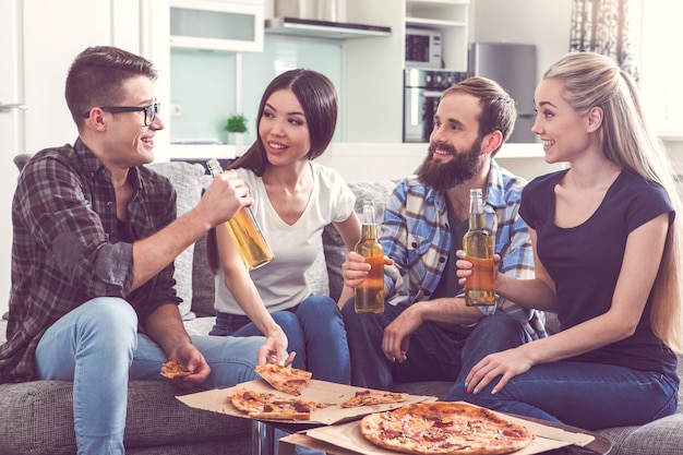 Amigos de fiesta juntos en el interior comiendo pizza