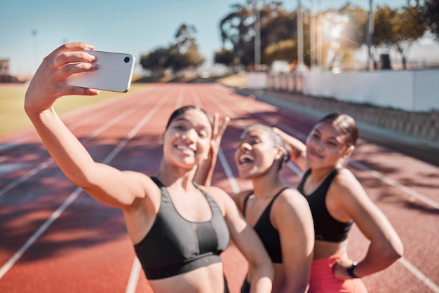 Amigos de fitness y selfie de un grupo de mujeres corredoras en una pista de atletismo para entrenar ejercicio y bienestar cardiovascular El teléfono deportivo y el equipo de chicas sonríen, se relajan y posan para una foto después del entrenamiento en el estadio