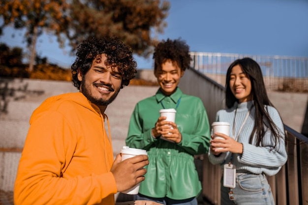 Amigos. Grupo de jóvenes tomando café afuera y hablando