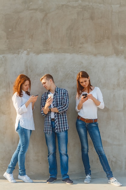 Amigos hablando al aire libre y usando sus teléfonos inteligentes