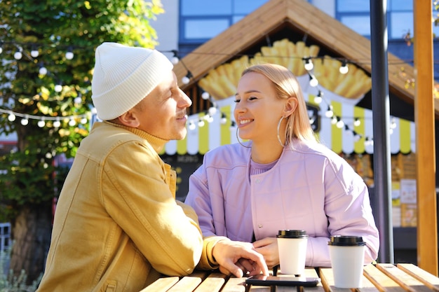 Amigos hablando bebiendo café en el almuerzo al aire libre bajo el sol primaveral en las calles de la ciudad Feliz pareja de trabajadores disfrutando de una cita de café juntos afuera