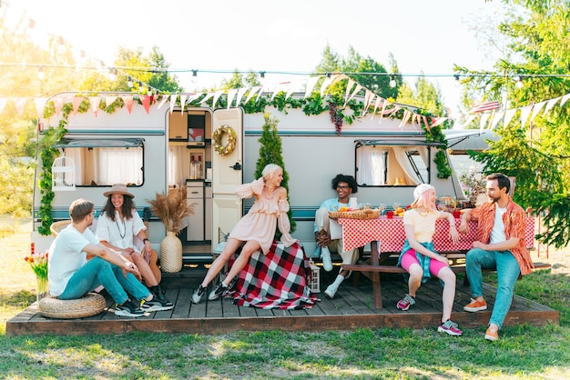 Amigos hacen un picnic con una caravana en un prado verde