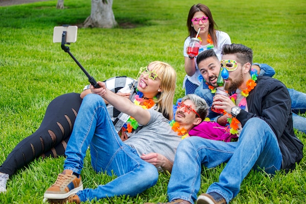 Amigos haciendo selfie en el festival de verano con máscaras y collares