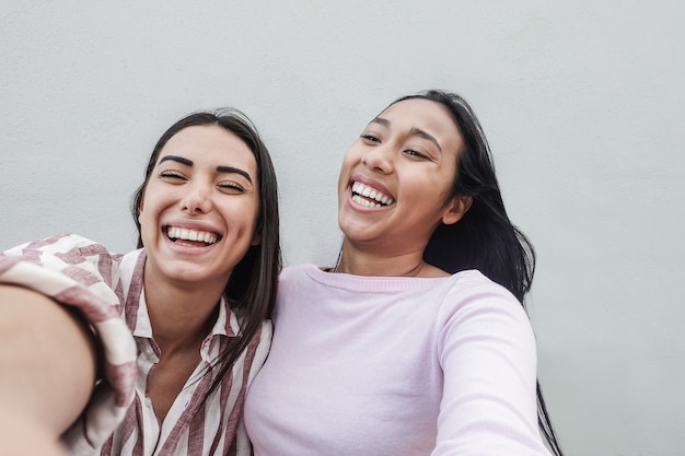 Amigos hispânicos felizes se divertindo fazendo selfie com o aplicativo para celular - concentre-se no rosto esquerdo da garota