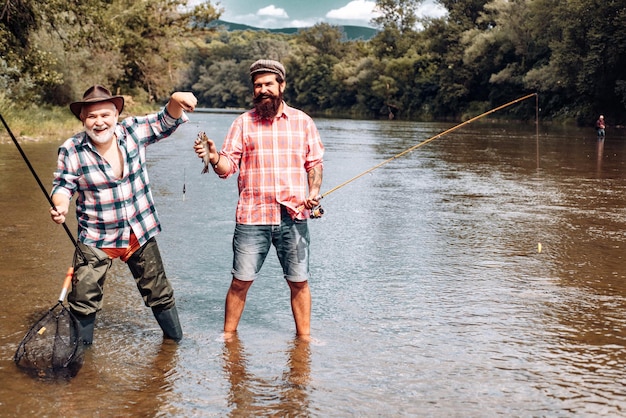 Amigos del hombre Retrato de un anciano alegre pescando Abuelo e hijo pescadores Hombre joven y un anciano pescando hilado en el río o lago