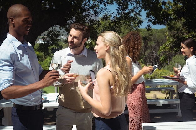 Amigos interactuando mientras toma una copa de vino en el restaurante