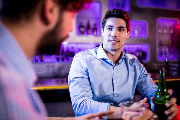 Amigos interagindo uns com os outros no balcão do bar enquanto toma cerveja