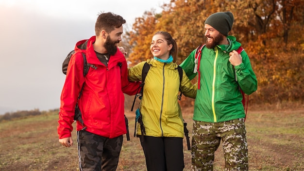 Amigos jóvenes positivos senderismo en la naturaleza de otoño