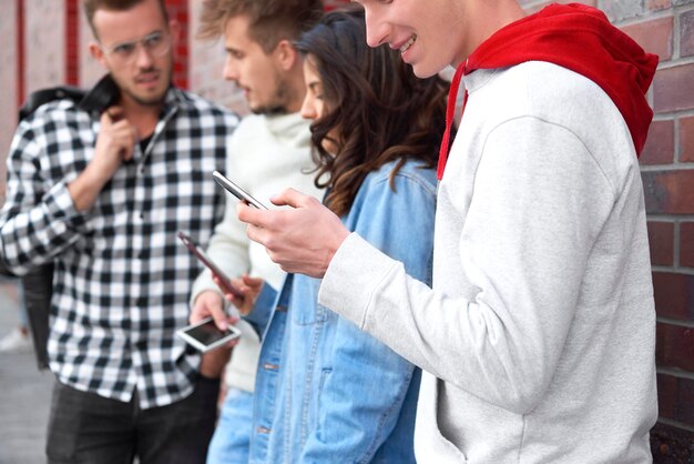 Foto amigos jóvenes usando teléfonos inteligentes mientras hablan en la ciudad