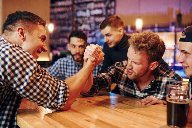 Los amigos juegan a la lucha libre Grupo de personas juntas en el interior del pub se divierten los fines de semana