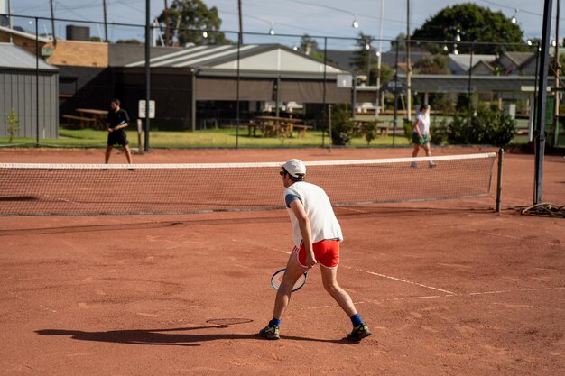 amigos jugando al tenis en una cancha de arcilla regando y embolsando una canca de arcilla haciendo mantenimiento de la cancha de tenis