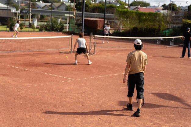 amigos jugando al tenis en una cancha de arcilla regando y embolsando una canca de arcilla haciendo mantenimiento de la cancha de tenis