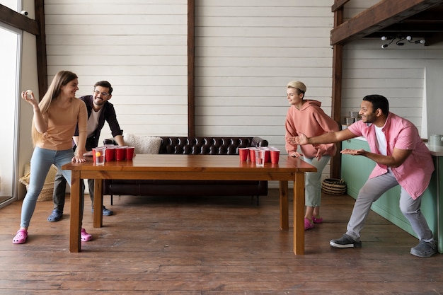 Amigos jugando Beer pong juntos en una fiesta