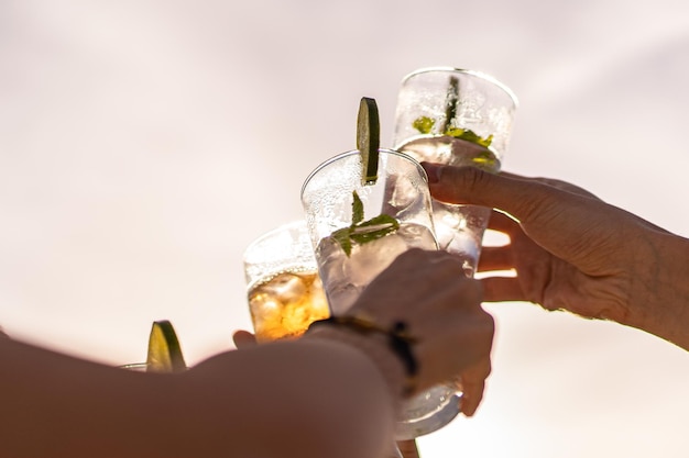 Amigos levantando copas de cóctel para un brindis de celebración contra el cielo en el verano