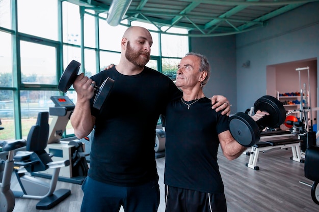 Amigos levantando pesas mientras están de pie en el gimnasio