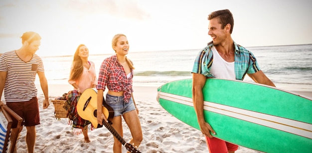 Amigos llevando una tabla de surf y una canasta.