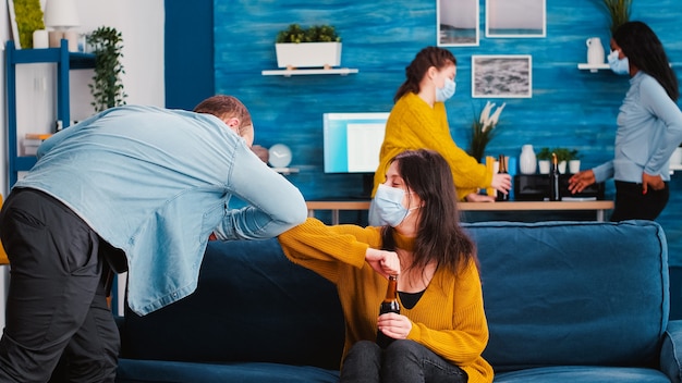 Amigos con mascarilla médica protectora saludan a sus codos manteniendo el distanciamiento social