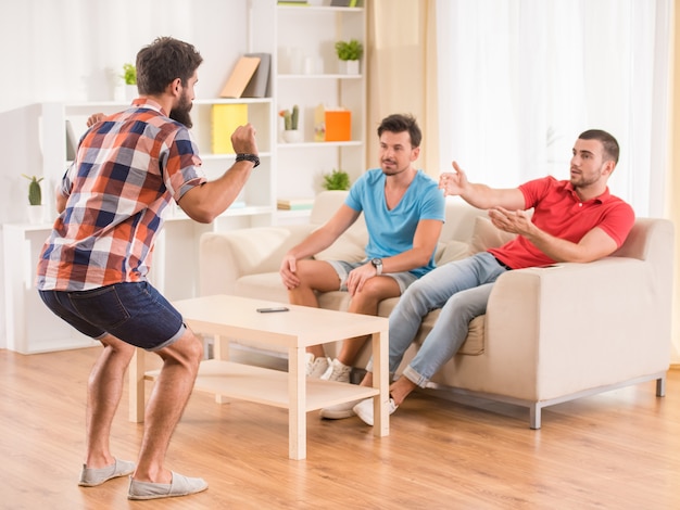 Los amigos masculinos felices jovenes se divierten en casa.