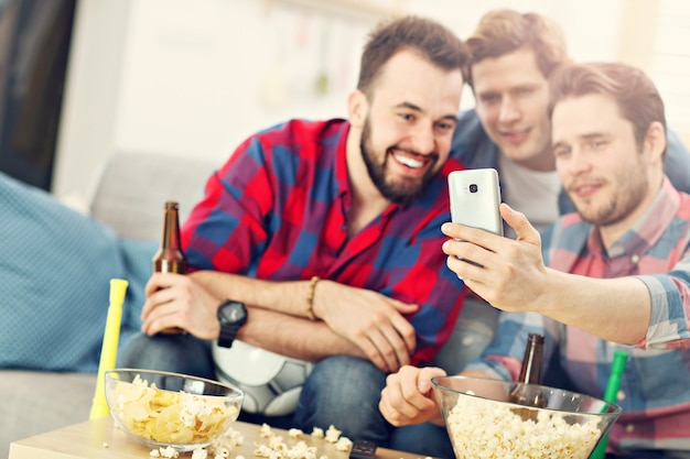 Amigos masculinos felizes torcendo e assistindo esportes na tv