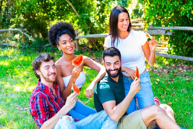 Foto amigos masculinos y femeninos comiendo sandía en el patio trasero