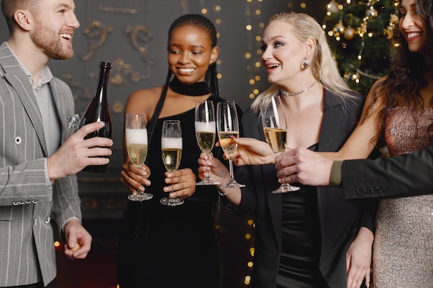 Amigos masculinos y femeninos en vestidos elegantes celebrando el Año Nuevo