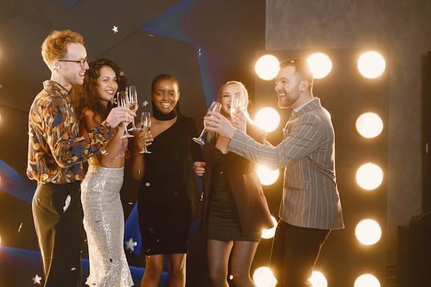 Amigos masculinos y femeninos en vestidos elegantes celebrando el Año Nuevo