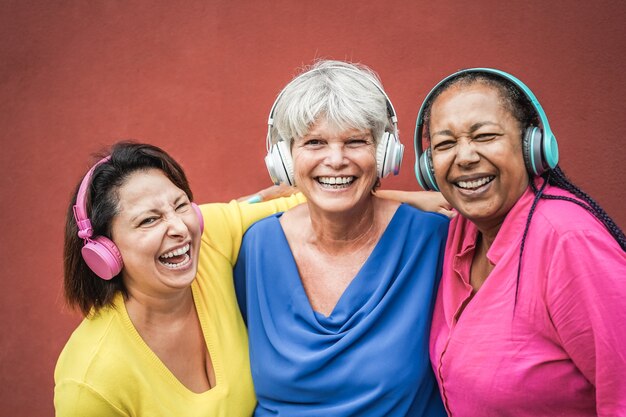 Amigos mayores multirraciales que se divierten escuchando música con auriculares - Centrarse en la cara de la mujer media