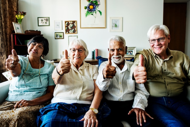 Amigos mayores que gesticulan los pulgares para arriba