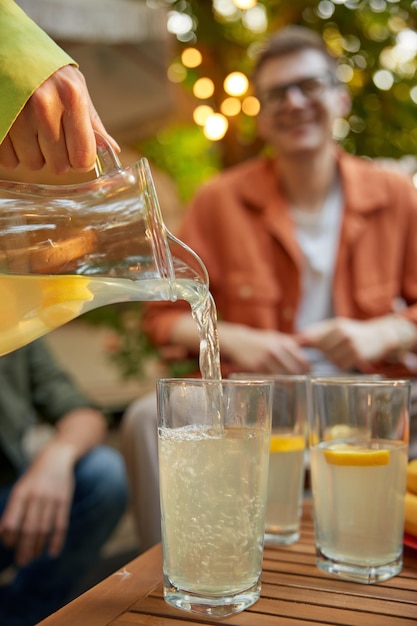 Amigos en la mesa con limonada fresca divirtiéndose en un picnic al aire libre.